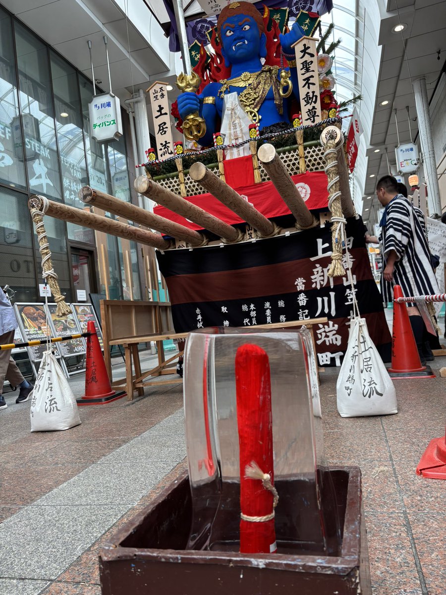 saichannel's tweet photo. 猛暑の下、飾り山前に涼やかな氷柱が出てました。
氷の中にある赤い筒は、山笠の「てっぽう」です。山笠の台上がりが手に持って舁き手を指揮や鼓���するために使う指揮棒の役割をします。
なかなか粋なヒンヤリ冷たい氷で、しばし凉を頂きました！
#博多祇園山笠 #jブリ　#Yuka　#Tuesday https://t.co/6TbOoiDACA