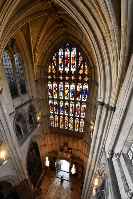 An aerial photograph of the large, stained glass Great West Window in Westminster Abbey, with the floor of the nave far below.