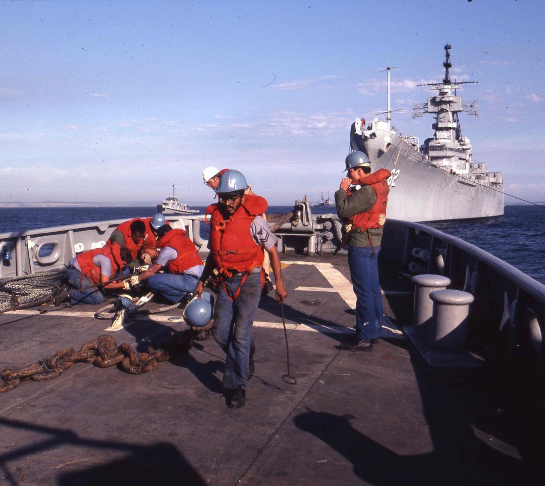 BattleshipNJ's tweet photo. July 1981 photo, sailors aboard the fleet tug USS Takelma (ATF-113) work her stern lines in Puget Sound. Behind them, under tow, is Battleship New Jersey, on her way to Long Beach, CA for refitting and reactivation. 

Today, Battleship New Jersey rests permanently in Camden, open for tours and ready to share the stories of the Navy sailors who helped her become the legend she is today. 

#Navalhistory