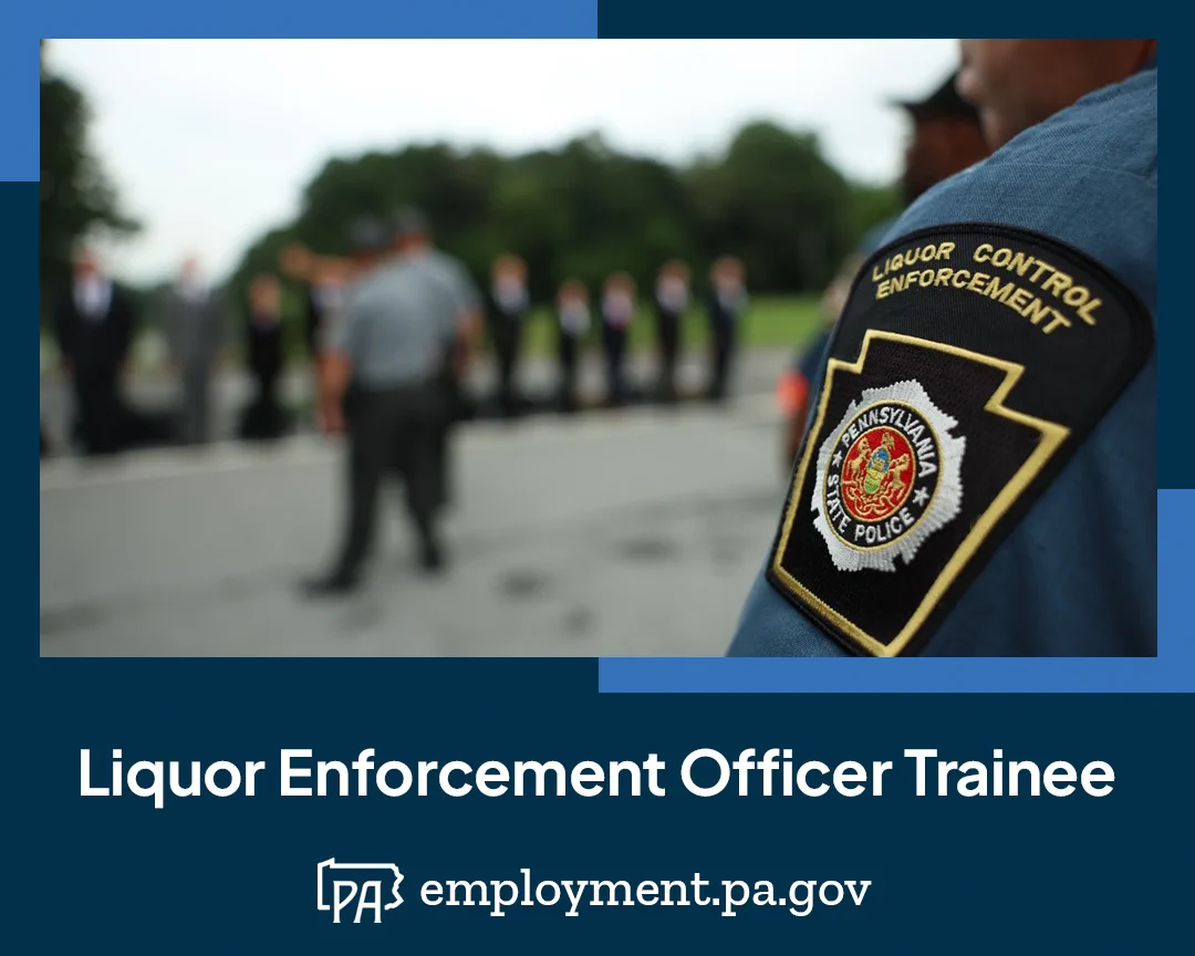 Close up of the Liquor Control Enforcement patch worn on a uniformed officer; in the unfocused background, new Trainees are lined up in front of an instructor on the first day of their training; the words Liquor Enforcement Officer Trainee, the Pennsylvania outline logo, and the URL employment.pa.gov
