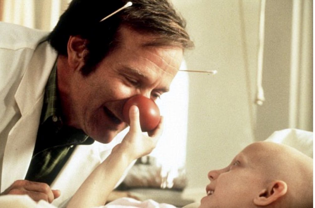 2StefanMoore's tweet photo. In the late ’90s in a hushed San Francisco Children’s hospital, a nurse freezes mid step in the hallway, fighting tears.  From inside one of the rooms comes the sound of a little boy, terminally ill, laughing so hard he can barely breathe.  She peeks in.  There’s Robin Williams, drowning in oversized scrubs, a red clown nose on his face, stethoscope swinging like a jump rope, doing every voice from every cartoon the kid has ever loved.  No cameras.  No manager hovering.  Just Robin, turning a sterile room into pure magic for one small human who’s running out of tomorrows.

Fast forward to 2003.  Same quiet mission in a different city, a ten year old with leukemia has days, maybe hours, left.  His dad has been a rock, no tears, not once, because his boy needs him strong.  Robin shows up unannounced.  Within minutes he’s conducting an invisible orchestra made of squeaky IV poles, belting an operatic love song to the heart monitor beeps.  The dad finally cracks but he’s not crying from pain, he’s crying because, for the first time in months, he’s laughing too.

Robin never told a soul about these visits.  Not Conan, not Billy Crystal, not the press.  When grateful families tried to shout his kindness from the rooftops, he gently shut it down. “That moment was theirs,” he’d say. “Not mine to talk about.”

One night in Denver, after a sold out show, he drove an hour each way just to meet a teenage girl whose favorite movie was Aladdin.  She knew every Genie line by heart.  When Robin burst in & launched into that wild blue whirlwind of a voice, “Ten thousand years will give you such a crick in the neck!” her whole face caught fire with joy.  Her mom said later he stayed way past visiting hours, sitting on the edge of the bed, trading stories like old friends, listening more than he performed.

Think about what that took.  Walking into rooms thick with grief.  No script, no director yelling “cut,” no second take.  Just a kid who might not wake up tomorrow, parents holding their breath & Robin choosing, every single time to step into the fire & pull out light.

He’d sit on the floor eating melted ice pops, hold tiny hands, let kids yank his beard & when it was over, he’d sit alone in his rental car for a long time.  Sometimes sobbing.  Sometimes just staring at the dashboard until he could drive again.

Nurses from Seattle to Miami knew the deal.  If Robin was in town doing stand-up, a call might come. “Tell no one,” he’d say.  “Especially not me if it ever leaks.”

He didn’t save lives in the medical sense but handed out something almost as rare.  Ten minutes, twenty minutes, an hour where a dying Child forgot they were dying.  Where a parent remembered their kid was still a kid.  Where laughter, impossible, ridiculous, defiant laughter, won a round against the darkest opponent there is.

That was Robin’s medicine.  Not a cure.  Just a reminder, fierce & tender, that even when the world is whispering “let go,” there’s still room to feel wildly, beautifully alive & maybe, just maybe, that’s the most healing thing of all. ❤️