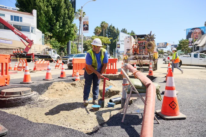 An LADWP technician addresses a pinhole leak in a large pipe in the WeHo area. Equipment and vehicles are visible as they prepare to restore water service