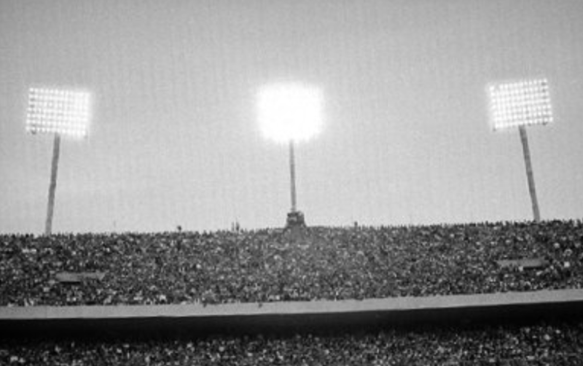 MXESTADIOS's tweet photo. Así era oiriginalmente la tribuna que ahora conocemos como "del Pebetero" en 1952, del Olímpico Universitario.
Tenía tres torres de alumbrado y, obviamente, no existía el pebetero olímpico.

Para los Juegos del 68 se quitaron esas torres y se crearon las que ahora conocemos, y se creó el pebetero.

Esta foto en blanco y negro es de un clásico Pumas-Politécnico, con un lleno espectacular y al lado, la misma imagen colorizada.