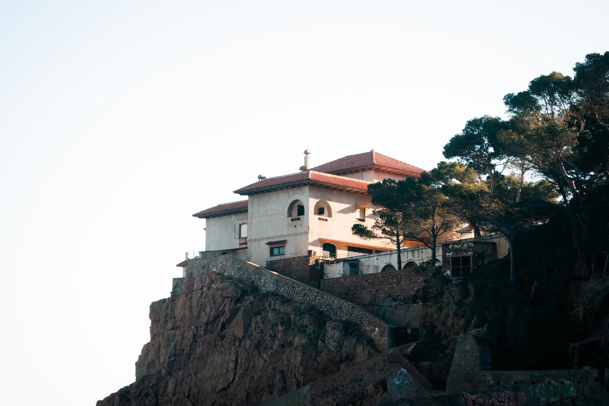 maisons's tweet photo. Villa méditerranéenne rises above a rugged rock face, its pale rendered walls, red tiled roofs and arched openings forming a layered composition of shade, stone and late light.

Photo: ✰ Saul Bandera Brotheridge / Pexels https://t.co/pVi06GgO1L