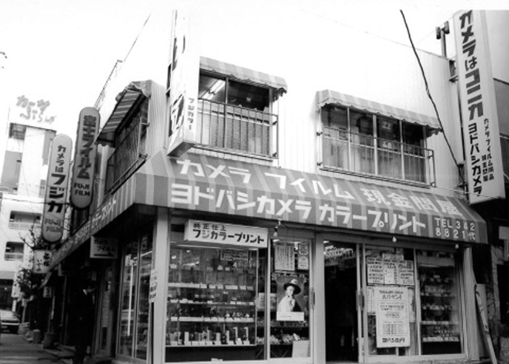 kantokuflash's tweet photo. 『ヨドバシ一号店』1971年頃・新宿西口

1960年に渋谷で創業した卸店「藤沢写真商会」が新宿に移転して「株式会社淀橋写真商会」になり、1971年頃から小売りも開始した。
当時は新宿西口一帯を旧地名の淀橋と呼ぶ人が多く、その地名にちなんで「ヨドバシカメラ」と名乗ったのだった。
