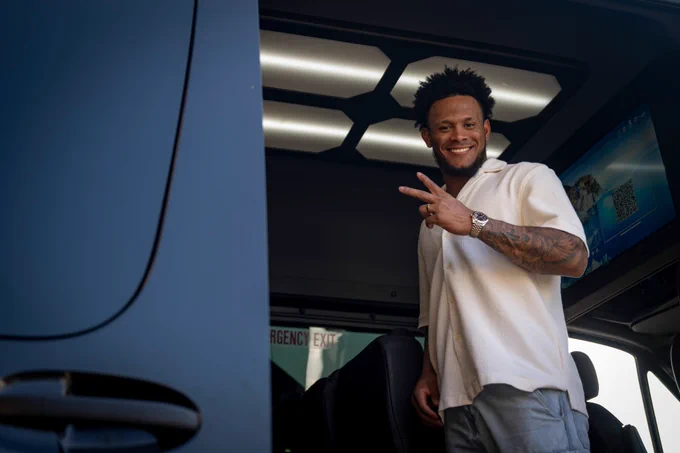 Ceddanne Rafaela holds up a peace sign while boarding a sprinter van at Citi Field. He is wearing a white shirt and jeans.