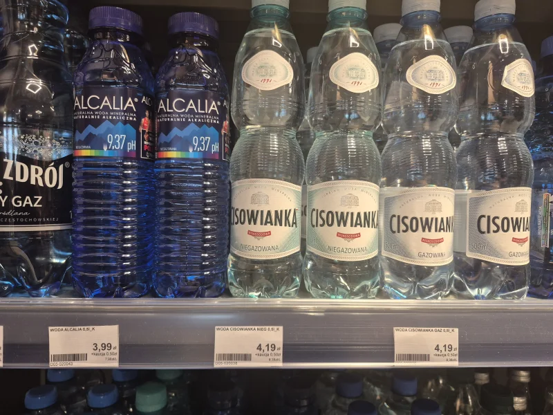 sknerus_'s tweet photo. Orlen podniósł ceny wody Cisowianka po sporze o 23% VAT na wodę.

Na stacjach Orlen wzrosła cena wody Cisowianka 0,5 l, która obecnie kosztuje 4,19 zł.

Producent Cisowianki, spółka Nałęczów Zdrój, złożył skargę do Komisji Europejskiej oraz pozwał Skarb Państwa, domagając się ponad 5 mln zł odszkodowania.

Zdaniem firmy obowiązujący system podatkowy ma charakter dyskryminujący - zwykła woda mineralna jest objęta 23% stawką VAT, podczas gdy słodzone napoje oraz wody smakowe z dodatkiem soku korzystają z preferencyjnej 5% stawki VAT.