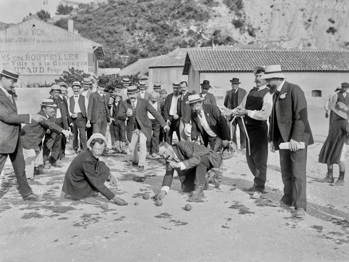 CeJour_Histoire's tweet photo. Le jeu préféré des Français a été inventé par deux hommes qui ne pouvaient plus marcher.

1907, La Ciotat. Sur le terrain de boules d'un café, on joue au jeu provençal. Une discipline exigeante : il faut courir, s'élancer, sauter, avant de lâcher la boule.

Assis sur une chaise, un homme regarde. Il s'appelle Jules Hugues, on le surnomme Lenoir. C'était une vedette du jeu. Les rhumatismes l'ont cloué là. Il ne court plus, il ne s'élance plus. Il fait rouler quelques boules à deux mètres, pour tromper l'ennui.

De l'autre côté du terrain, le patron du café l'observe. Il s'appelle Ernest Pitiot. Lui non plus ne peut plus jouer : il est unijambiste.

Alors il lance à son ami une idée toute simple. Reste planté là. On trace un cercle au sol, on met le cochonnet à cinq mètres, et tu joues sans bouger les pieds.

En provençal, pieds plantés se dit pèd tanca.

Le jeu se répand comme une traînée de poudre. En 1910, La Ciotat organise déjà le premier concours officiel. Aujourd'hui la fédération compte plus de 300 000 licenciés, et on y joue de Bangkok à Montréal.

Chaque été, sur une place de village, quelqu'un trace un rond dans la poussière. Sans le savoir, il refait le geste de deux infirmes qui voulaient juste continuer à jouer avec leurs amis.