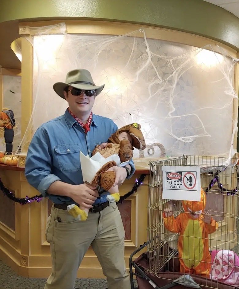PatchDMD's tweet photo. In memory of Sam Niell (@TwoPaddocks), here’s a photo of my Halloween costume a few years ago. 

I was Dr. Alan Grant and my two boys were dinosaurs. 

Side note, my son who’s there in the “electric cage” wagon? #JurassicPark is STILL his favorite movie. https://t.co/riBNsvetzi