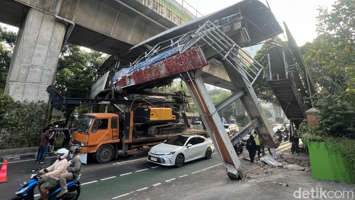 LambeSahamjja's tweet photo. truk nyangkut di jpo tendean, jaksel :
- truk pengangkut ekskavator tersangkut di jpo jl. kapten tendean, jaksel, dini hari (~00.30 wib)
- sopir tidak perhitungkan tinggi maksimal muatan, 
- diduga karena main hp saat nyetir
- akibat: tiang penyangga jpo rusak parah, nyaris roboh, anak tangga jpo tidak bisa digunakan
- dishub dki sarankan hindari jl. kapten tendean arah blok m
- jalur alternatif: jl. hr rasuna said, jl. gatot subroto, jl. kemang raya, & jl. antasari