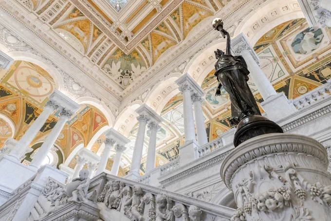 Bronze statues of women holding torches of electric light sit on the newel posts of the ornately designed staircases in the Great Hall of the Library of Congress Jefferson Building. Photo by Shawn Miller.

