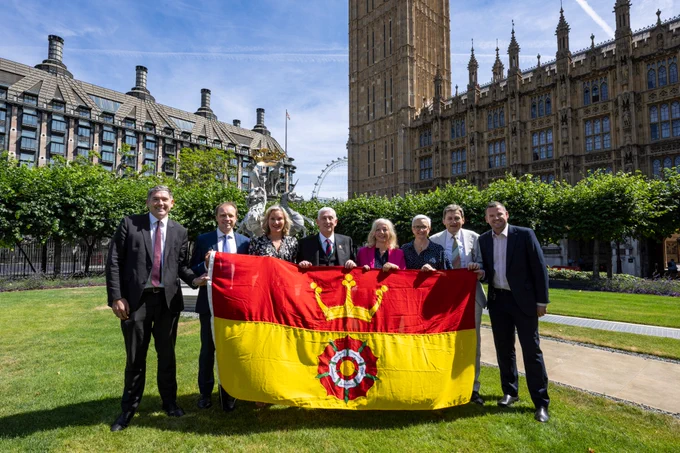 Commons Speaker with a group of Hampshire MPs posing with Hampshire flag in New Palace Yard.
