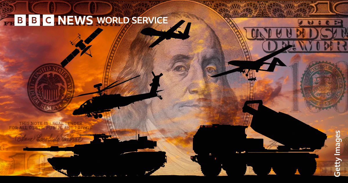 Silhouettes of military hardware including tanks, helicopters, drones, a fighter aircraft, a missile launcher and a satellite, are layered over a US $100 bill featuring Benjamin Franklin. A Federal Reserve seal is visible against a dramatic orange sky, illustrating the financial cost and economic interests linked to war. BBC News World Service branding appears in the top left corner.