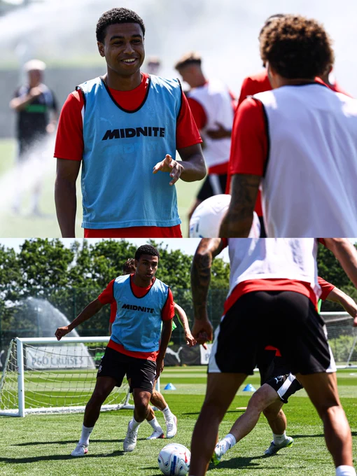 A split screen image of Shea Charles in training, wearing a blue Midnite branded bib over his red training top and black shorts in both images. The top image shows him smiling with teammates. The bottom image shows him chasing after the ball during a drill.