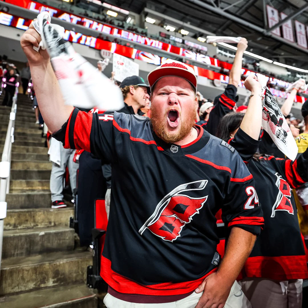 Photo of a fan cheering in a black Canes jersey at a playoff game