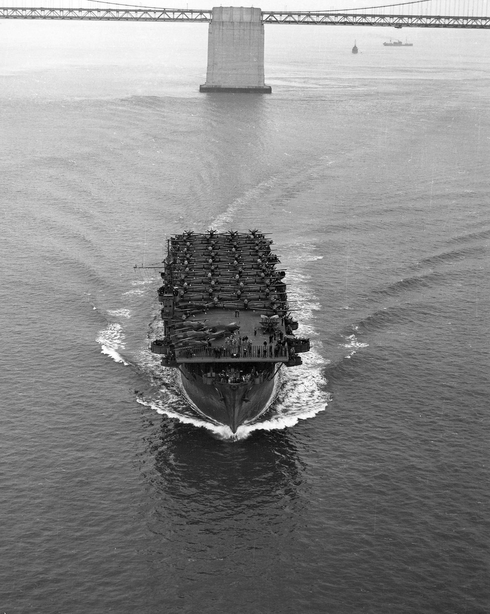HiddenHistoryYT's tweet photo. Escort carrier USS Altamaha transporting a deck load of P-51A Mustang fighters has just left Alameda, passed under the San Francisco Bay Bridge (background) and steams toward the Golden Gate, 16 July 1943 https://t.co/ET423LEHMr