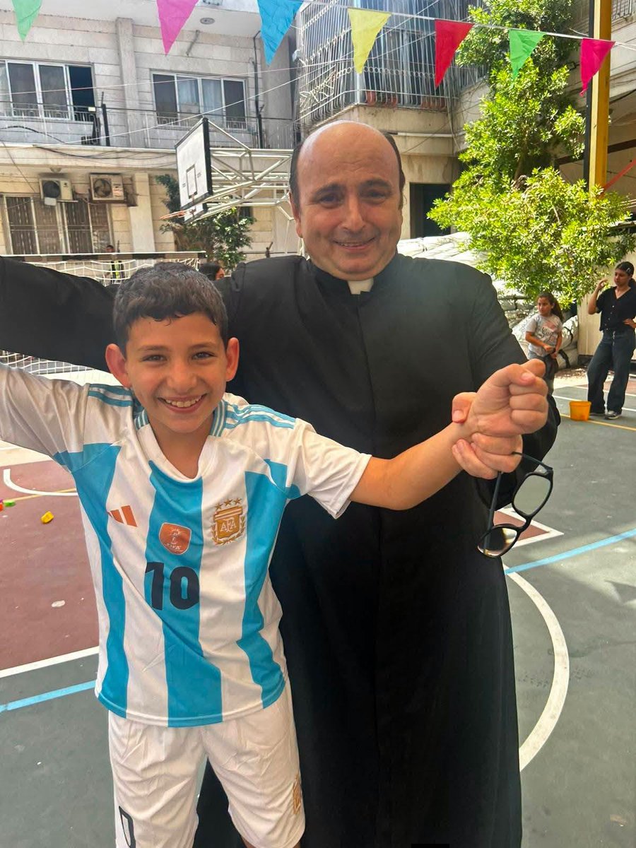 IhabHassane's tweet photo. Palestinian Christian children celebrate Argentina’s victory over England alongside Argentine priest Father Gabriel Romanelli at the Holy Family Church in Gaza, as Argentina advances to the FIFA World Cup Final. https://t.co/Tn4SA5c4Of