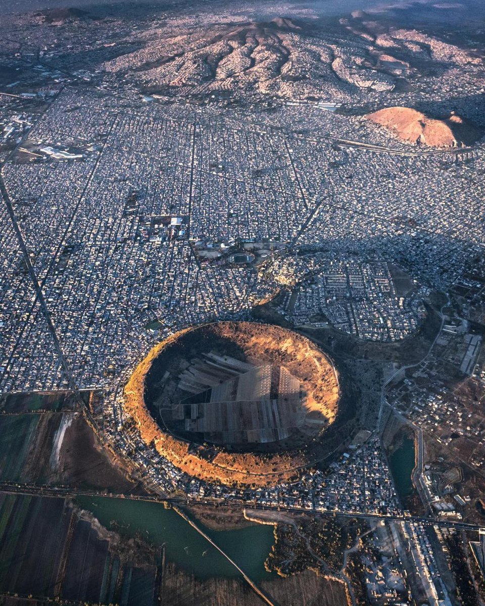 EspirituCurioso's tweet photo. Este es uno de los paisajes más surreales de México. 😱

Sí, ese enorme círculo casi perfecto que ves en medio de la ciudad es el cráter de un volcán.

Se trata del volcán de Xico, en Valle de Chalco, Estado de México. Su cráter mide aproximadamente 1.4 kilómetros de diámetro y es tan simétrico porque no es un volcán cualquiera. Los estudios geológicos lo clasifican como un volcán monogenético, es decir, nació durante un solo episodio eruptivo y después quedó inactivo para siempre. Además, se formó cuando el magma entró en contacto con el agua del antiguo lago de Chalco, provocando una explosión que creó un anillo de toba y el enorme cráter que todavía puede verse desde el aire.

Lo más sorprendente es que, cuando este volcán surgió, todo su alrededor era parte del antiguo sistema de lagos del Valle de México. Con el paso de miles de años los lagos fueron desecándose, llegaron caminos, colonias y avenidas, hasta que la expansión urbana terminó rodeándolo casi por completo.

Aunque desde arriba parece una isla en medio del concreto, el interior del cráter ha sido utilizado durante generaciones para la agricultura gracias a que sus suelos volcánicos son especialmente fértiles. Es uno de esos lugares donde la historia geológica y la vida cotidiana terminaron compartiendo el mismo espacio.

Pocas imágenes muestran tan claramente cómo un paisaje formado por la naturaleza hace miles de años terminó convertido en parte de una de las zonas urbanas más grandes del planeta.

Espíritu Curioso, ¿imaginas que existía un lugar así? ¿Conoces otro lugar en el mundo igual a este?

📸 IG: santiago_arau