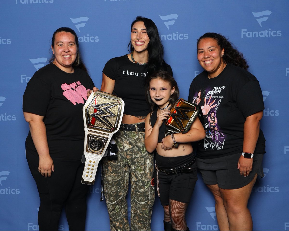 BritStevens2's tweet photo. My niece got to be in the Rhea look a like contest at fanatics fest and also lucky to get a photo with the goat herself @RheaRipley_WWE 💜 thank you for being a role model for all the kids. We love you Rhea!! https://t.co/6GpceJu5IR