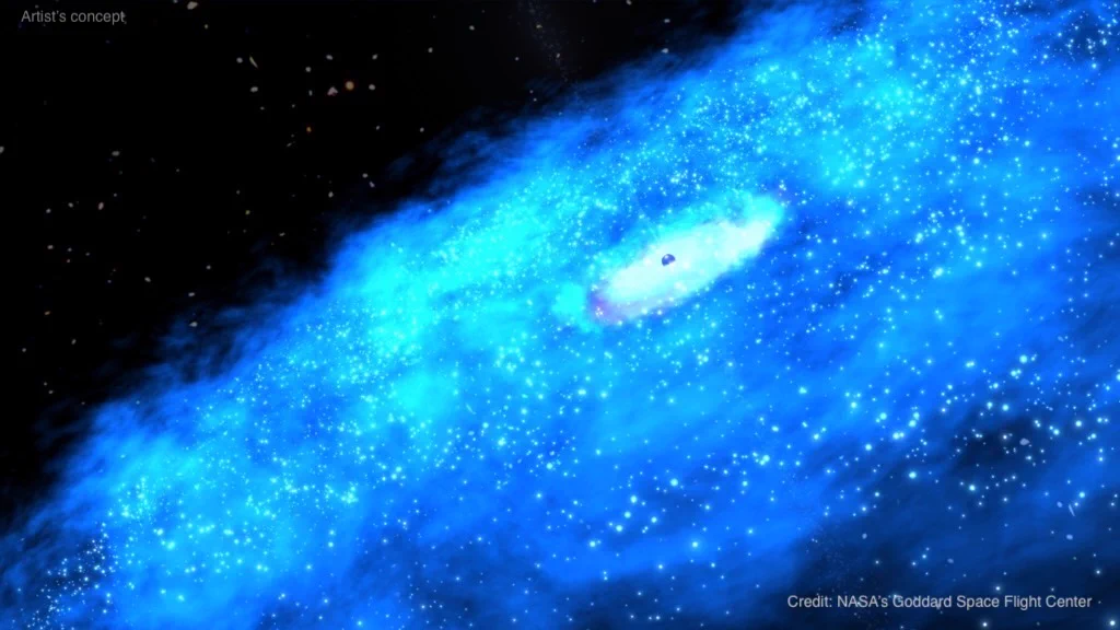 Most of the image is taken up by a hazy disk of electric blue material that represents the galactic disk of a blazar. Dotted around that hazy disk are lots of individual stars. At the middle the disk glows white with a small black bubble embedded in the very center. The image is watermarked “Artist’s concept” and “Credit: NASA’s Goddard Space Flight Center.”
