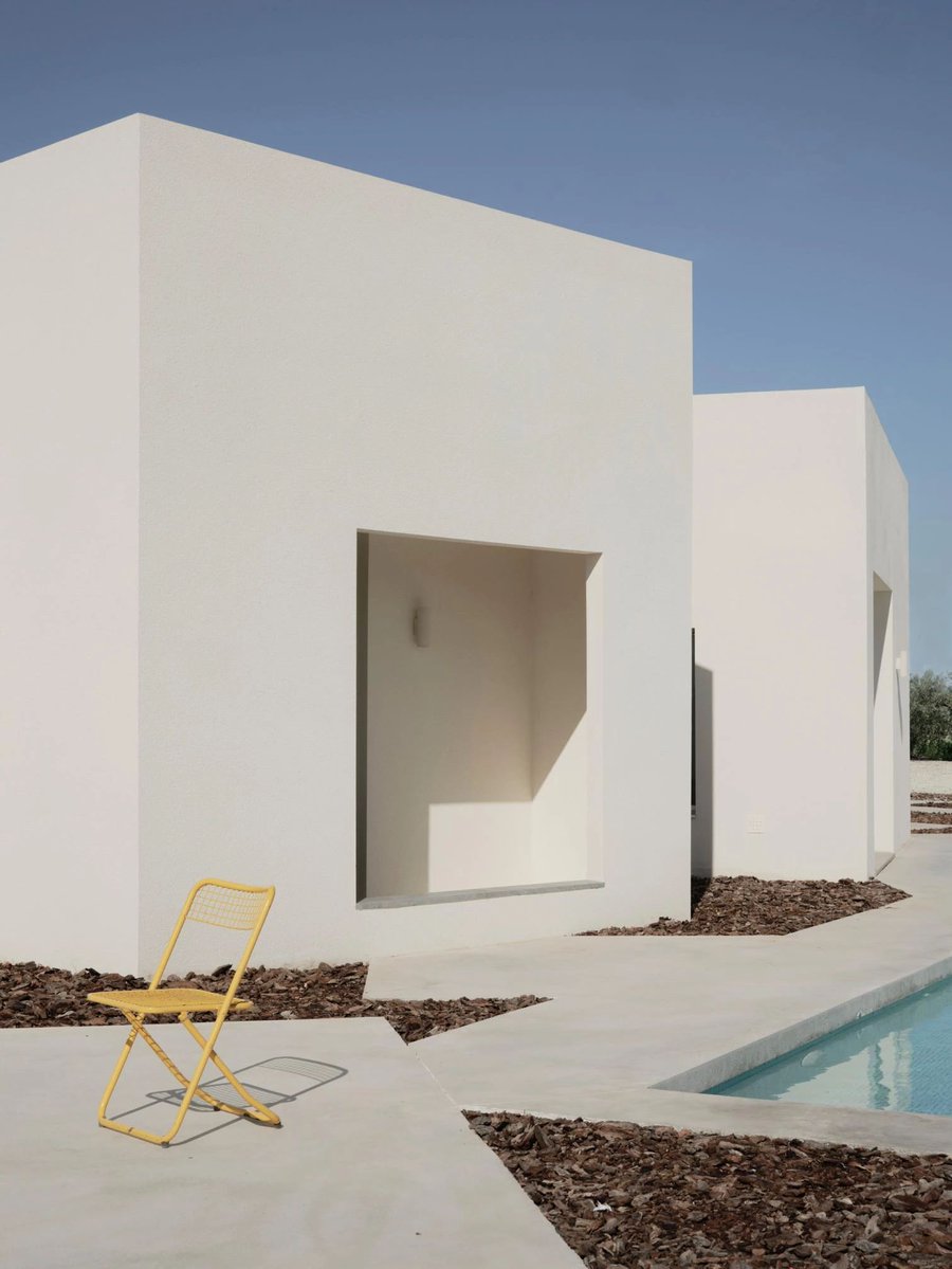 arquitect_viva's tweet photo. Casa AM14 en Lorca
Especie
https://t.co/Oa6CVF83ZK
La Casa AM14 está situada en la huerta de Lorca, en el corazón del valle del Guadalentín. Concebida como una casa que aspira a ser un pequeño pueblo, el proyecto se integra en una parcela delimitada únicamente por olivos y campos de alcachofas. La vivienda se organiza mediante la concatenación de nueve volúmenes independientes, cada uno destinado a una función específica, como cocinar, comer, descansar, trabajar o almacenar. Su disposición, con ligeros giros y separaciones entre piezas, favorece la entrada de luz natural desde distintos ángulos y genera pequeños patios que amplían la vida doméstica hacia el exterior.