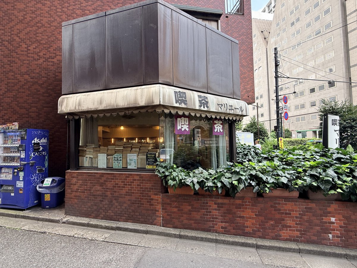 1qbz's tweet photo. ヤクザ（上のマンションを根城にしている）の行きつけの喫茶店、銃で狙われにくくするために本が積んである、とは本当なのだろうか https://t.co/1ydeO2ar2z