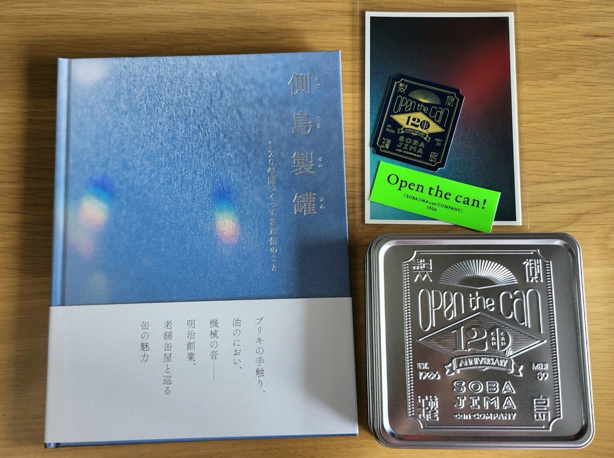 moti_1126's tweet photo. 側島製罐さん（@sobajimacan）からクラファンの返礼品をいただきました！ハードカバーもステッカーも記念缶も全てが格好良い！！
特に缶のエンボスとハードカバー表紙の質感が気持ち良くてしばらく撫でていました☺
拝読するのが楽しみです。ストレッチゴールの達成、本当におめでとうございます！ https://t.co/5Pc0ZTfri4