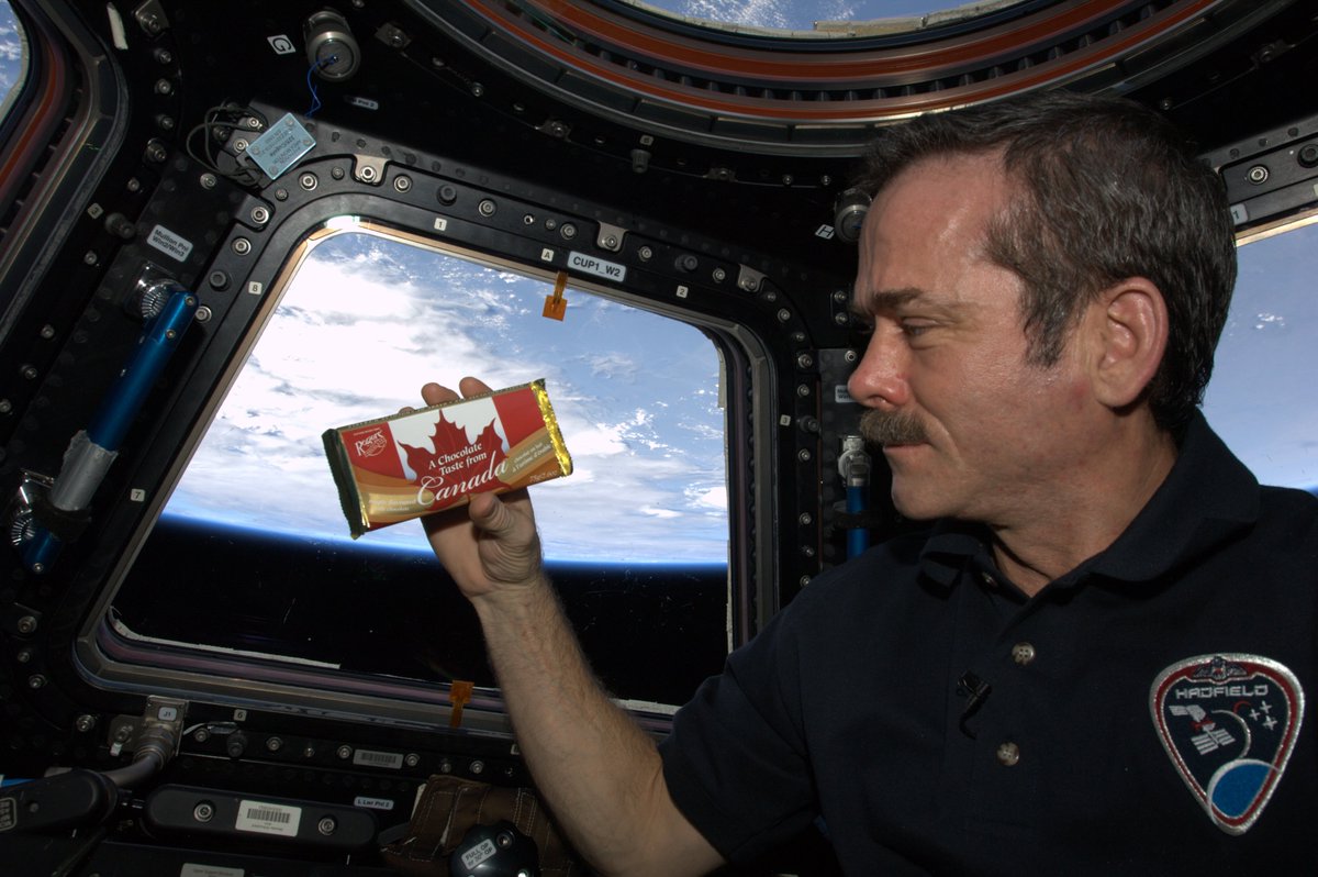 Cmdr_Hadfield's tweet photo. Chocolate tastes good, no matter where you are. 
We keep a chocolate wall on the International Space Station, a variety of types velcroed there for handy grabbing as we float by. Great energy snack & treat - delicious & doesn't spoil. 
Especially nice when it's chocolate from home. 
(chocolate selfie taken inside the cupola, Earth below)