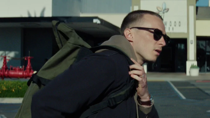 From Lucky. Drew Starkey as Cary walks with a backpack slung over his shoulders. He is wearing sunglasses.