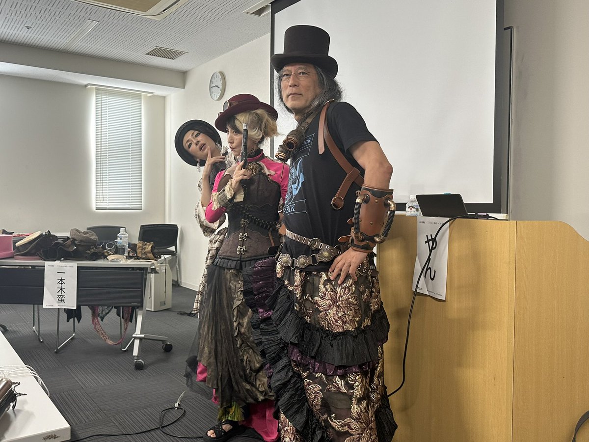 CptBuchi's tweet photo. 今年のSF大会も終わって1週間
遅くなりましたが自分の企画を振り返ります。
「蛮ちゃんと学ぶスチームパンクファッション」
やんさんのスチームパンクに関する知識がとても面白く、ぜひ皆さんに紹介したいと思ったのがこの企画の始まりです。
聞き手を蛮先生に��願いすれば企画として成立すると思い、お声がけさせていただきました。さらに内容を練る中で、「蛮先生ご自身に実際に衣装を着ていただいたら面白いのではないか」という話になり、今回の形に落ち着きました。
当日はきくまこ先生にも飛び入りでご参加いただき、大変盛り上がりました。
参加者の皆様に楽しんでいただけたようで何よりですし、暗黒星雲賞でも次点���選ばれるなど、大変嬉しい結果となりました。
#hellcon2026 #日本SF大会