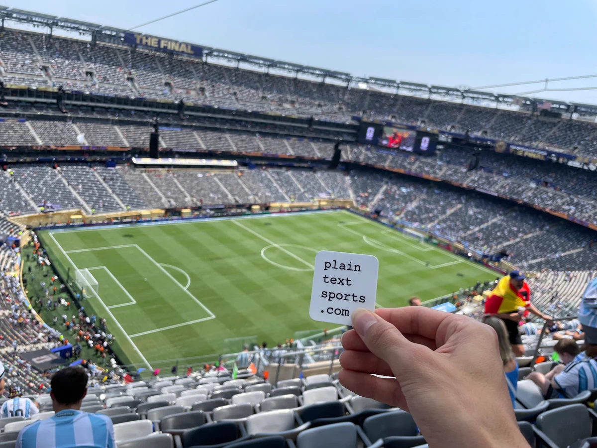 Me holding a plaintextsports.com sticker at the World Cup Final