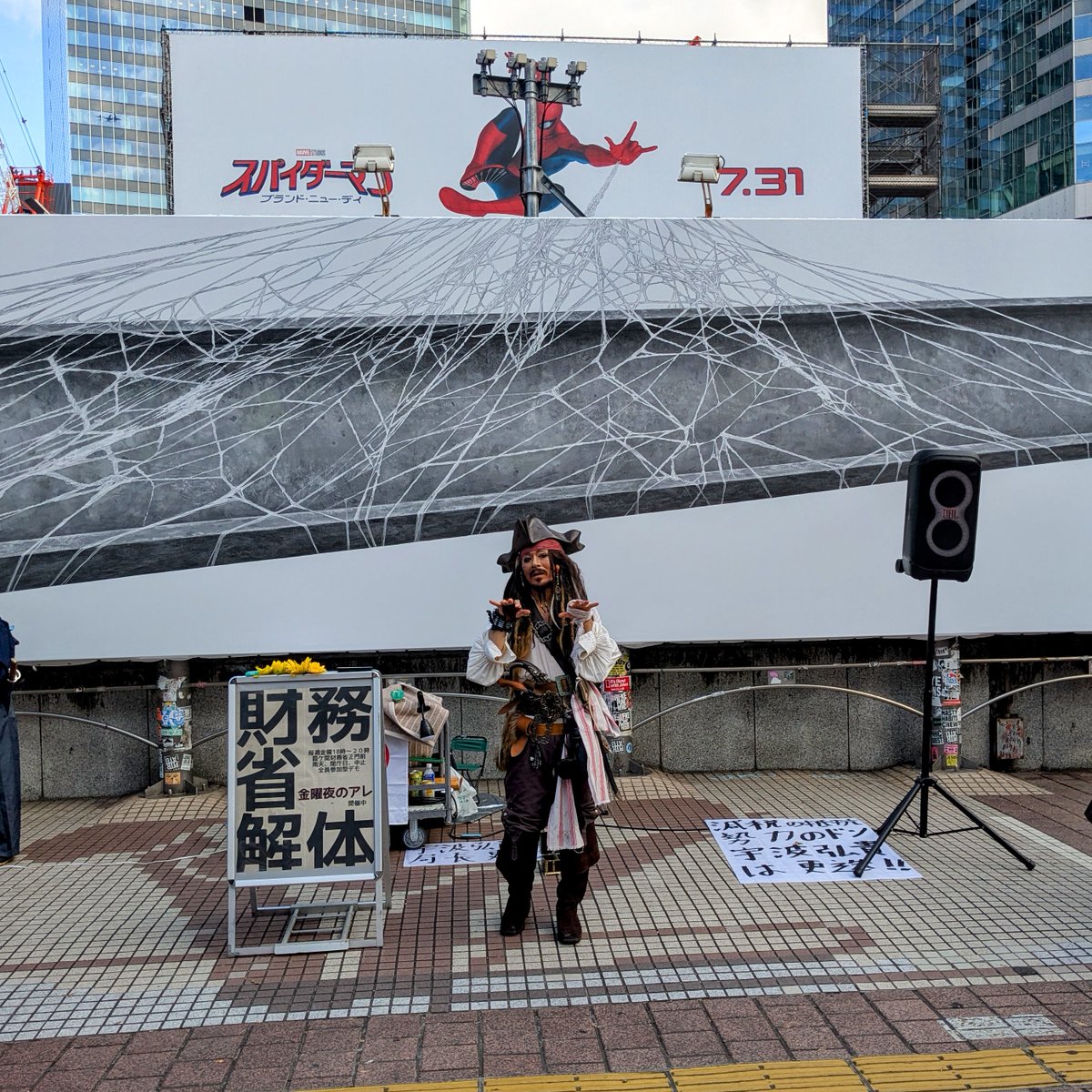 mrjeffu's tweet photo. I saw a crowd of tourists gathered around a Jack Sparrow cosplayer in Shibuya on Saturday afternoon.  
I think very few of the people taking pictures realized he was standing next to a sign advocating fringe conspiracy theories about Japan's Ministry of Finance. https://t.co/5koFEDIh76