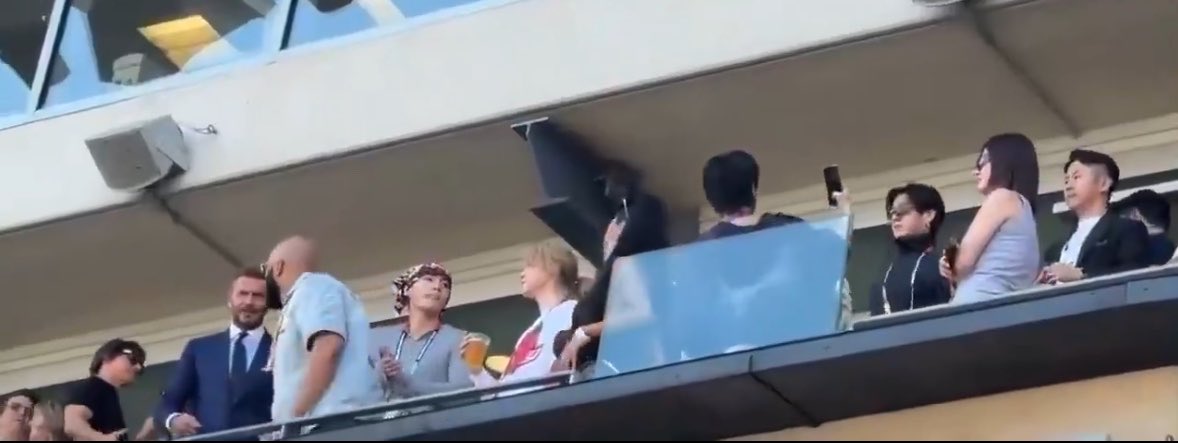 hourjinnie's tweet photo. Seokjin taking selfies while watching the game and being handed a beer! 🍺 

BTS are standing next to Tom Cruise &amp; David Beckham! 

JIN AT FIFA WORLD CUP
BTS AT WORLD CUP 2026
#BTSxWORLDCUP2026 
#BTSHALFTIMESHOW https://t.co/rXilLlEm51