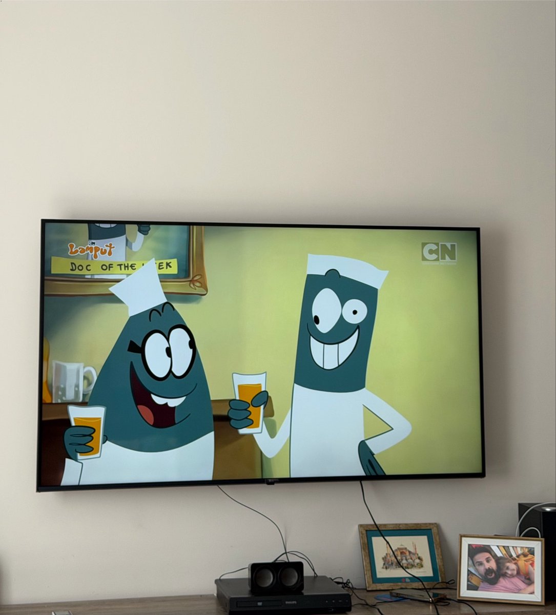 VeysiCe's tweet photo. Sessiz Zehir:
Yeğenlerim birkaç gün bize geldi. Normalde evde televizyonu neredeyse hiç açmam. Ancak talepleri üzerine birlikte Cartoon Network’ü açtık. İlk dakikalar eğlenceliydi. Sonra fark ettim: konuşma yok. Diyalog yok. Anlamlı cümle yok. Sadece saçma sapan hareketler, abartılı mimikler, sürekli bağırış, koşuşturma ve anlamsız ses efektleri ile tutum ve tavırlar. Karakterler birbirine bakıyor, bir şeyler yapıyor ama hiçbir şey söylemiyor. konuşmak yasaklanmış adeta…

Eski çizgi filmleri hatırlayın. Tom ve Jerry bile sessizdi ama hikâyesi vardı, mizahı zekiceydi. Bugs Bunny, Scooby-Doo, Dexter’ın Laboratuvarı, Powerpuff Girls… Karakterler konuşurdu. Diyalog kurardı. Problem çözerdi. Kelime dağarcığı gelişirdi. Çocuk hem eğlenir hem de dil öğrenirdi, sebep-sonuç ilişkisini görürdü, empati kurardı. Şimdi ise ekranda sadece görsel gürültü var. Beyin hiçbir şey üretmek zorunda kalmıyor. Sadece izliyor. Tepki veriyor. Tüketiyor.
Abarttığım düşünülebilir ama bence bunlar tesadüf değil.
Çocukların zihinsel gelişimini kösteklemek için bilinçli olarak tasarlandığına inanıyorum. Konuşma olmayan, sadece hareket ve ses efektinden ibaret içerikler, dil gelişimini yavaşlatır. Kelime dağarcığını kısırlaştırır. Dikkat süresini kısaltır. Hayal gücünü pasifleştirir. En önemlisi mentalizason becerisini azaltarak reaktif devinimi artırır. Bu da bizi düşünemeyen tepkisel olarak çalışan bireyle haline getirir. Çocuk “neden” ve “nasıl” sorularını sormayı bırakır. Çünkü soracak bir şey kalmamıştır. Hikâye yoktur, sadece dizi dizi absürt hareket vardır. Beyin, karmaşık düşünce yerine anlık uyarıya alıştırılır. Tıpkı sosyal medya algoritmaları gibi: hızlı, yüzeysel, bağımlılık yapıcı…
Kimse “çocukların zekâsını düşürelim” diye toplantı tutanağı tutmuyor belki. Ama sonuç aynı. Ekran karşısında saatlerce oturup hiçbir şey öğrenmeyen, sadece “eğlenen” çocuklar. 
Daha az konuşan, daha az sorgulayan, düşünme yetisi körelmiş, anlatmaya değil haz ve anlamsızlığa mahpus olmuş ve daha kolay yönlendirilen nesiller. Aileler “zararsız” diye düşünüyor çünkü şiddet yok, küfür yok. Oysa asıl tehlike sessizce geliyor: zihinsel tembellik.
Eski çizgi filmler çocuklara “konuşmayı, düşünmeyi, hayal etmeyi�� öğretirdi. Yeniler ise “sadece izle, tepki ver, unut” diyor. Bu bir gerileme değil, bir tercih. Ve bu tercih, çocuklarımızın zihinlerini yavaş yavaş köreltiyor.
Ve burdan uyarmak istiyorum bu eğlence değil; sessiz bir zehir.