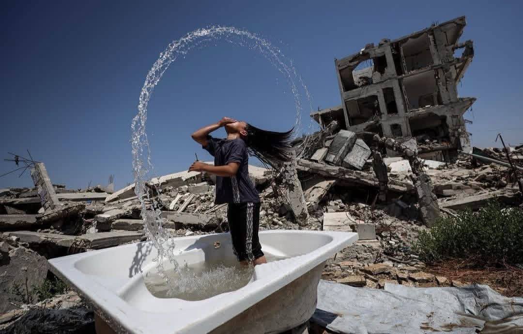 QudsNen's tweet photo. Children in Gaza try to escape the intense summer heat among the rubble of their destroyed homes, using small amounts of water to cool themselves amid the ongoing Israeli siege. https://t.co/a6jeQrLVft