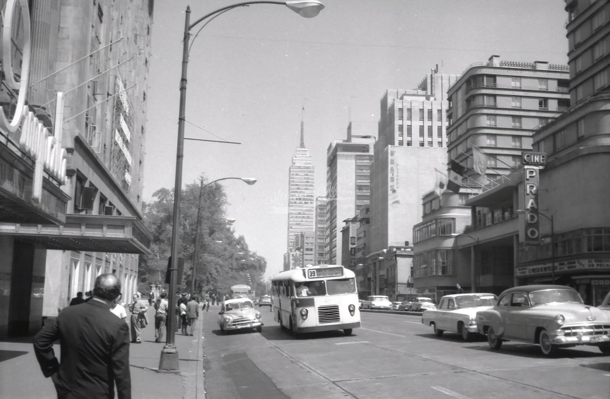 mexdeayer's tweet photo. Un autobús del transporte público, conocido popularmente como "chato", se aproxima a un paradero ubicado frente al Hotel Regis, sobre la Avenida Juárez, en una escena cotidiana de las décadas de 1950 o 1960. La fotografía muestra a una persona esperando la llegada del transporte, reflejando la dinámica diaria de una de las vialidades más importantes de la Ciudad de México.
Del lado derecho de la imagen se aprecia el Hotel del Prado, además de otros edificios emblemáticos que formaban parte del paisaje urbano de la época. Al fondo sobresale la Torre Latinoamericana, que ya se perfilaba como uno de los símbolos arquitectónicos más representativos de la capital.
Con el paso de los años, este sector de la ciudad experimentó una profunda transformación. Los terremotos del 19 de septiembre de 1985 modificaron de manera definitiva el entorno, provocando la desaparición de varios inmuebles históricos y dando paso a una nueva configuración urbana.
En la actualidad, la Avenida Juárez presenta un aspecto muy diferente. La circulación vehicular se realiza en un solo sentido con dirección al Centro Histórico y el transporte público que antes recorría esta vialidad dejó de prestar servicio en este tramo. Sin embargo, las fotografías de aquella época conservan el recuerdo de un paisaje urbano que forma parte de la memoria histórica de la Ciudad de México.

AGN