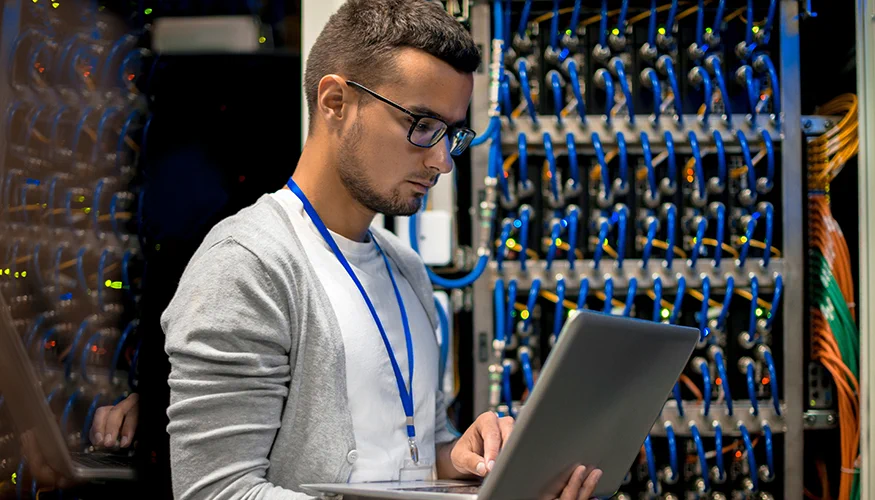person holding a laptop while standing in front of a supercomputer