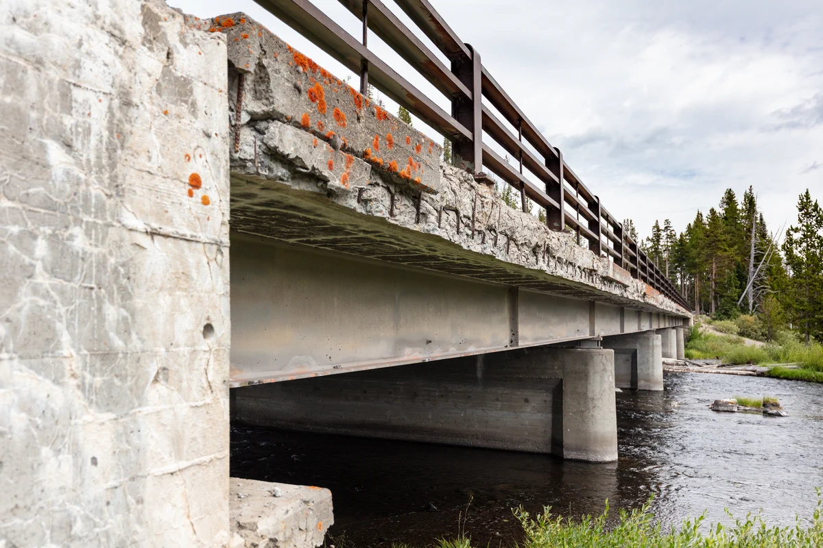 A crumbling bridge over a calm river.