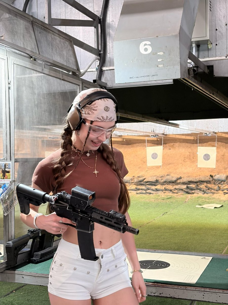 LunarTally's tweet photo. Outdoor range, wind and gear sounds mixing, oddly calming. Double braids with headscarf, crop top and white pants, soft lines against hard equipment. Eyes on the target, everything else fades, just breath, sight, and the pull. Focus itself is cool enough 🎯🤍 https://t.co/4w0rgnFrmx