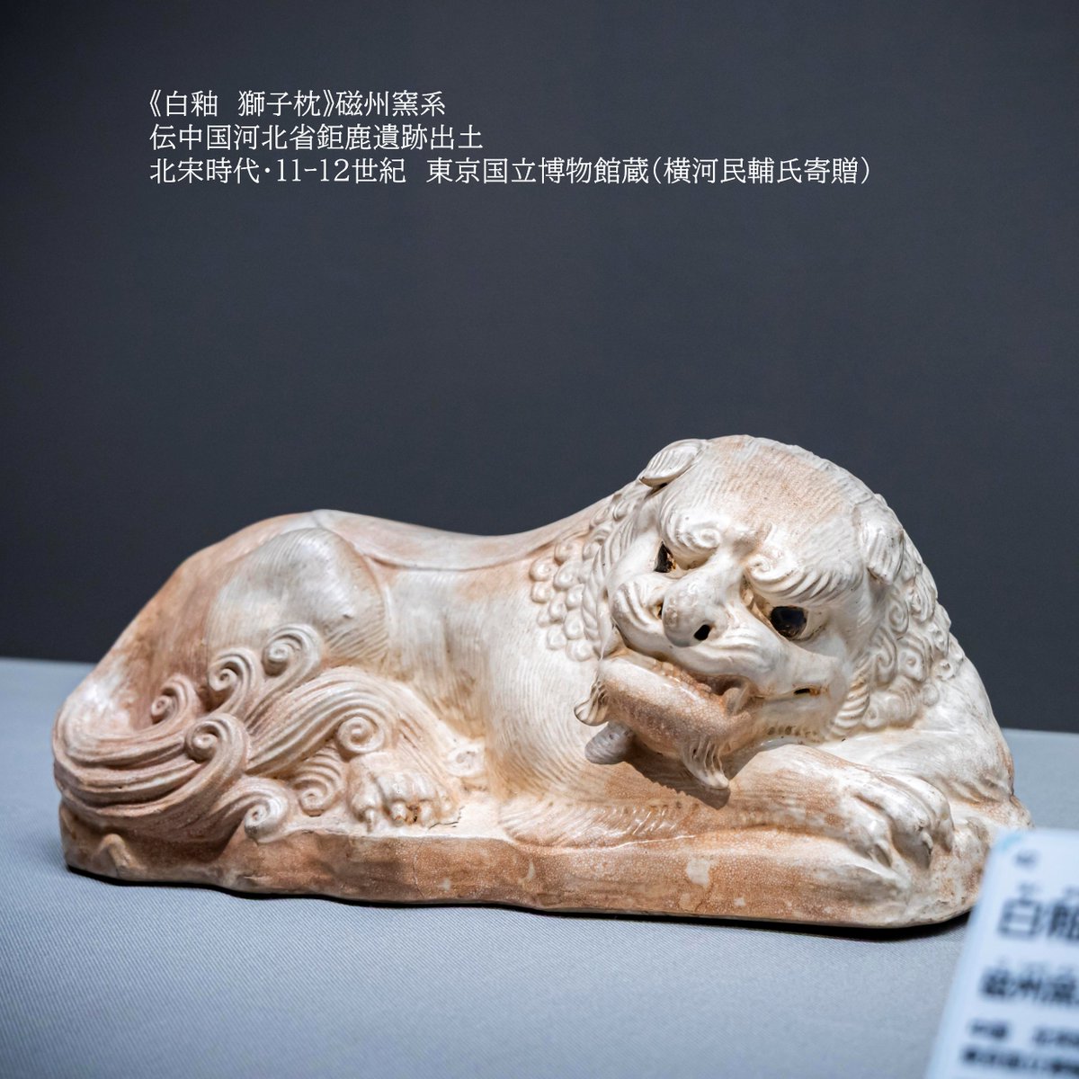 suikoden2026's tweet photo. 【ここに注目👀＃水滸伝展⑪】
＼寝心地はいかに🤔 北宋の枕／
悠々と横たわる獅子をかたどった陶製の枕。背の掛物の文様や毛並みまで繊細に刻まれ、黒釉を点じた目には生き生きとした表情が宿ります。
当時、猛獣形の陶枕は家内安全を祈願する吉祥物として用いられ、獅子形だけでなく虎形の枕も多く作られたのだとか。
この作品は、鉅鹿（きょろく）という町の遺跡から出土したもので、実際に北宋の人々の生活の中で使われていました！
陶製の獅子枕、ちょっと硬そうですが寝心地が気になりますね🦁