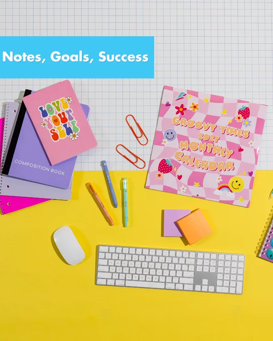 Colorful workspace with a 2023 monthly calendar, notebooks, sticky notes, and a keyboard on a bright yellow desk.