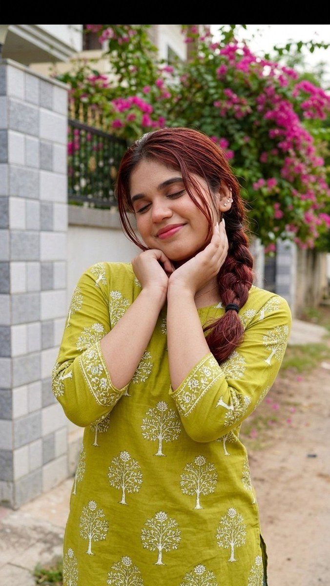 oye_samia's tweet photo. Feeling as bright and cheerful as these blooms!🌼

Prompt: Hyper-realistic full-body portrait of a young South Asian girl outdoors. Wearing lime/olive-green cotton kurti with white tree/floral block print, three-quarter sleeves, dark blue jeans. Long black hair in loose side braid with side-swept strands. Small stud earrings, natural minimal makeup, soft pink lips. Playful pose with hands under chin, head tilted, eyes closed, smiling. Background: boundary wall with grey-white tiles, vibrant pink bougainvillea, dirt path, natural daylight. Don’t change her face.