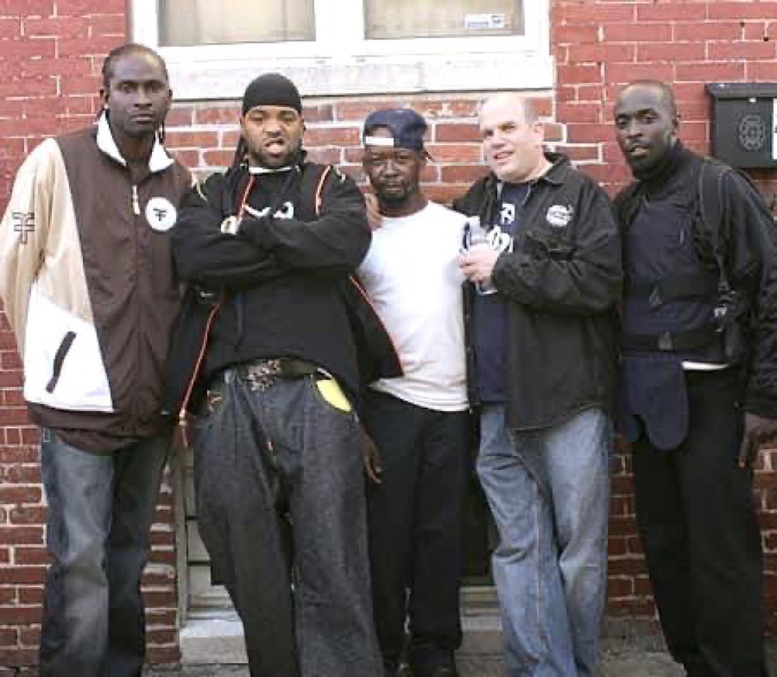 Ziggys_Duck's tweet photo. Snot Boogie actor Juan Beckham (middle) was a wardrobe assistant on #TheWire. The BPD pulled him over one night, searched his trunk &amp; found police uniforms intended for use on the show. He was locked up &amp; car impounded, even after HBO verified the uniforms were props for filming. https://t.co/WgyAVoA4Qw