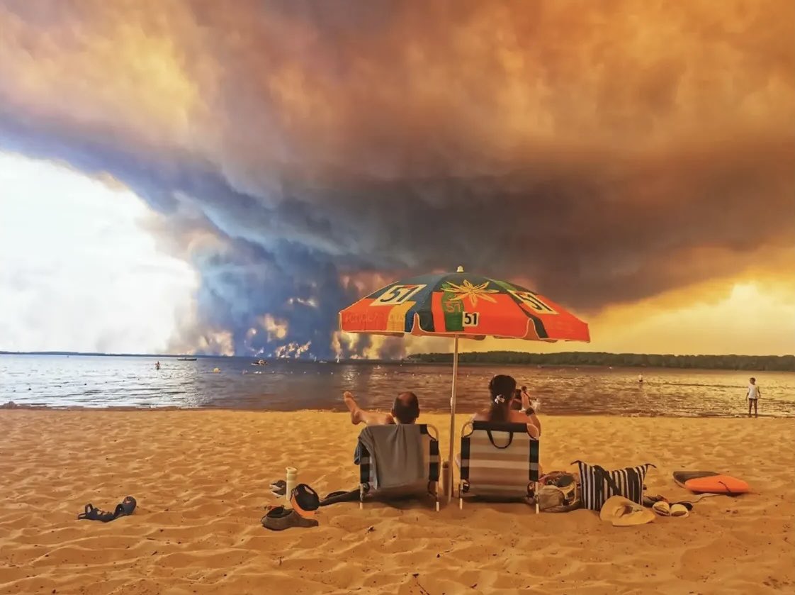 yannickhoppe's tweet photo. Le 24 juillet 2026, sur la plage du Moutchic, à Lacanau, commune située à proximité de l’incendie qui ravage la Gironde, Maximilien Lamy, photographe pour l’@afpfr réalise une image qui restera sans doute comme l’une des photographies les plus marquantes de la crise climatique en France. Le plus saisissant, pourtant, ce n’est pas l’incendie. C’est le calme.

Deux personnes sont assises face à l’océan. Un parasol leur offre un peu d’ombre. Autour d’elles, des serviettes, des tongs, une glacière. Une scène de vacances comme il en existe des milliers chaque été.

Puis le regard se lève.

Une immense colonne de fumée engloutit l’horizon. Le ciel disparaît sous des nuances d’ocre, de gris et de noir. La catastrophe est là. Pas au bout du monde. Pas dans un futur hypothétique. Ici. Maintenant. �� quelques kilomètres d’une plage où l’on continue pourtant à profiter du soleil.

C’est toute la force du cliché de Maximilien Lamy. Il ne montre pas deux réalités qui s’opposent. Il montre une seule et même réalité. Celle d’un monde où le dérèglement climatique n’est plus une menace abstraite, mais le décor de notre quotidien.

L’un des vacanciers photographie la scène avec son téléphone. Ce geste est devenu presque banal. Nous photographions les incendies, les inondations, les canicules, les records de température. Nous partageons les images, nous commentons les chiffres, puis nous passons à la catastrophe suivante. L’urgence est partout. L’action, elle, reste désespérément en retard.

Car cette photographie raconte aussi un immense échec politique.

Voilà plus de trente ans que les scientifiques alertent. Plus de trente ans que les rapports s’accumulent, que les conférences internationales se succèdent, que les gouvernements promettent des ruptures qu��ils repoussent sans cesse. Pendant ce temps, les intérêts économiques continuent trop souvent de l’emporter sur l’intérêt général, les reculs environnementaux sont présentés comme du « bon sens » et chaque nouvelle réglementation écologique devient le prétexte d’une bataille idéologique.

À force de tergiverser, le pouvoir politique a laissé s’installer l’idée que l’adaptation suffirait là où il faudrait transformer. On s’habitue aux mégafeux, aux sécheresses, aux canicules comme hier on s’habituait aux bulletins météo. L’exception devient la norme. L’impensable s’installe dans le paysage.

Le génie de Maximilien Lamy est de ne désigner personne. Son image est plus puissante qu’un réquisitoire. Elle nous place tous dans le même cadre : citoyens, entreprises, médias, gouvernements. Personne ne peut prétendre regarder cette photographie de l’extérieur.

Les grandes photographies survivent aux événements qu’elles racontent. Parce qu’elles capturent davantage qu’un instant : elles saisissent un basculement.

Dans quelques décennies, lorsque les historiens chercheront une image capable de raconter les années où l’humanité connaissait parfaitement les conséquences du dérèglement climatique sans trouver la volonté politique d’agir à la hauteur de l’urgence, ils reviendront peut-être vers cette photographie de Maximilien Lamy.

Non parce qu’elle montre un incendie spectaculaire.

Mais parce qu’elle raconte, en une seule image, le grand paradoxe de notre temps : une civilisation qui contemple lucidement le monde en train de brûler, sans réussir, collectivement, à changer le cours de son Histoire.