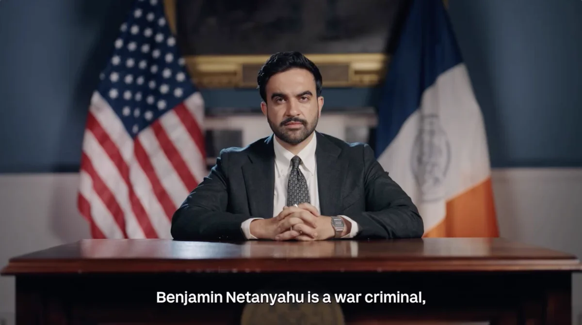 Mayor Mamdani is seated at a desk, with the American and New York City flags behind him. The text at the bottom reads, "Benjamin Netanyahu is a war criminal."