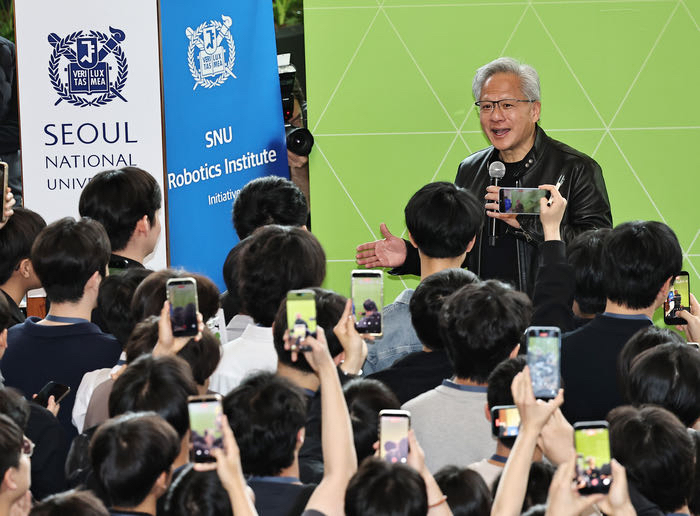 Person speaking to a crowd with phones at Seoul National University event.