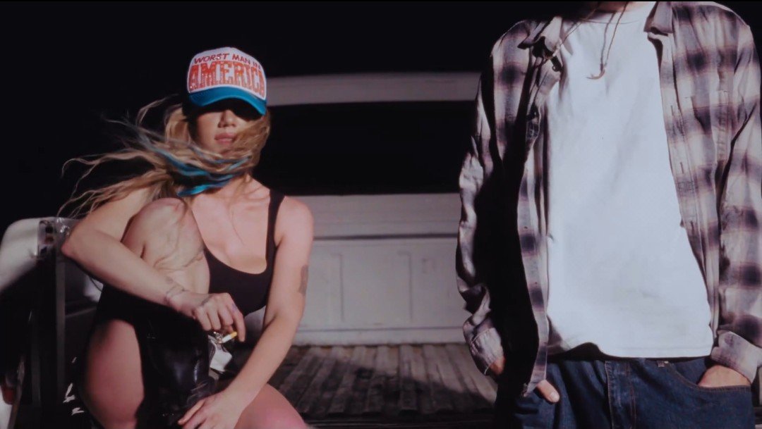 LUCIDNIGHTM4RE's tweet photo. this shot from the brand new chanels mv being the exact opposite to the worst girl in america album cover: she's sitting down and he's standing and out of frame, inverted colours, new title on the cap, this is PERFECT slayyyter I love you so much https://t.co/eRG5HtSHbd