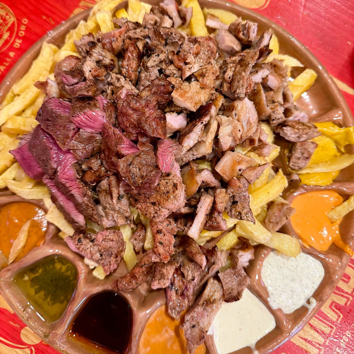 AlfonsoCSuarez's tweet photo. Una fuente de patatas fritas caseras, entrecot de ternera, solomillo de cerdo y pechuga de pollo con ocho salsas por 24 euros.

Eso es Gandarío, uno de los bares que más me gusta de Madrid.

No esperes alta cocina ni florituras. Es comida de batalla, pero de calidad. Y una cosa que valoro muchísimo: cada tipo de carne está cocinada en su punto ideal.

Las tablas van desde la más pequeña, con dos salsas, hasta la mayor (la que pedí), con ocho salsas. Las eliges entre las 14 opciones que hay.

Hacía mucho que no iba y ahora me pregunto por qué he tardado tanto en volver. De hecho, hasta me pareció mejor de lo que lo recordaba.

Si hay que poner un pero, son algunas salsas. No todo puede ser de 10. Sobre todo, no me gustó el mojo verde, que era aceite puro. Pero en conjunto está cerca del 9.

📋 Ficha exprés:
📍 Gandarío — C. de Gaztambide, 28, Chamberí (Madrid)
🍽️ Precio medio: 16 €/persona
⭐ Recomendado para: cuando tienes mono de carne con patatas fritas
🌟 Mi nota: 8,8/10