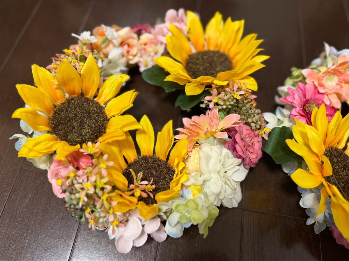 AI_think_child's tweet photo. 夏をテーマにしたリース作り🌻✨

それぞれ好きな花を選びながら自由にデザイン😊

「ここがいいかな？」
「やっぱりこっち！」

花の向きや角度、色の組み合わせにもこだわりながら、何度も並べ替えていました。

同じ材料を使っても、それぞれ違った雰囲気に。

グルーガンは熱いので、取り付けは大人がお手伝いました。
夏らしいお気に入りの作品になりました☺️🌼