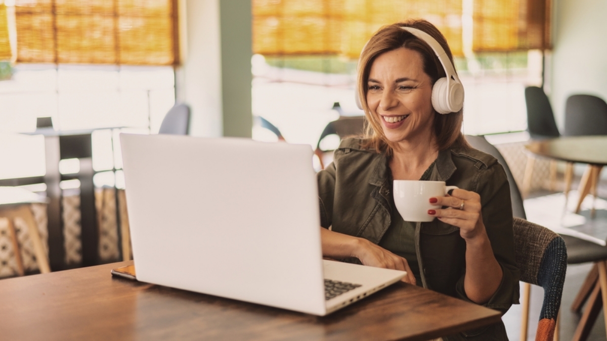 Borrower on their couch with their laptop or mobile phone, relaxed but engaged with coffee, headphones